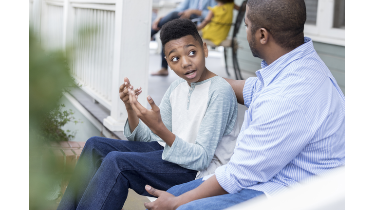 Confused preteen son talks to father on front porch