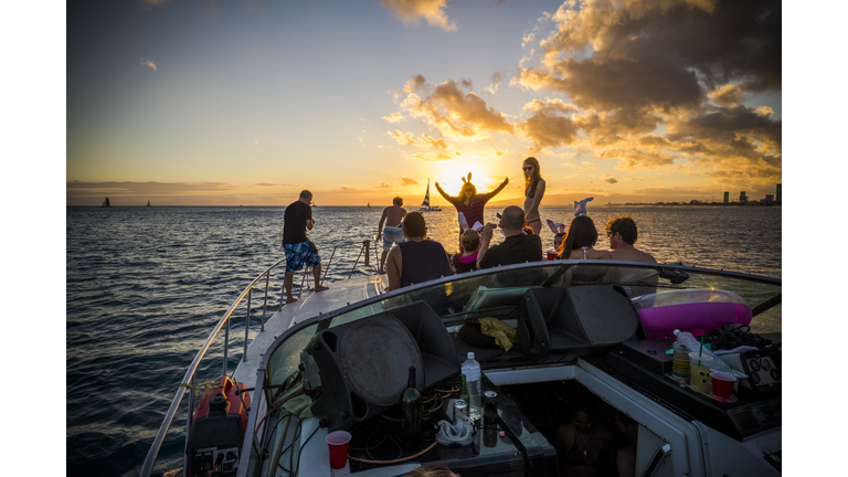 Friends party on yacht at sunset