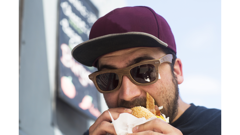 Male customer eating hamburger from fast food van