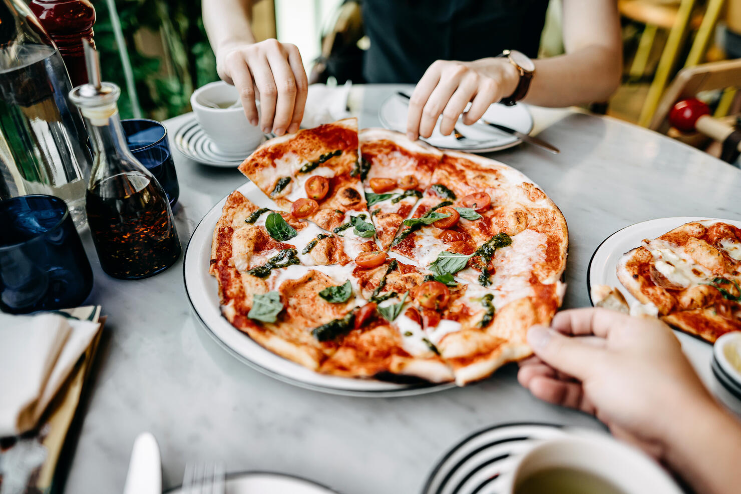 Close up of couple getting and sharing slices of freshly made pizza and enjoying meal in an Italian restaurant