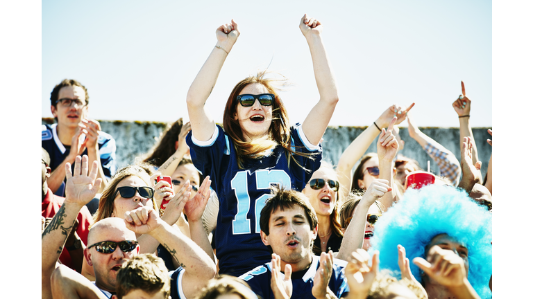 Female football fan standing in stadium cheering