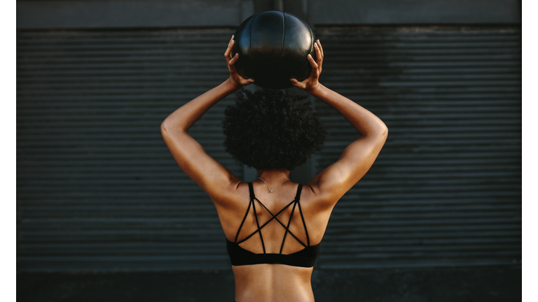 Muscular woman working out with fitness ball