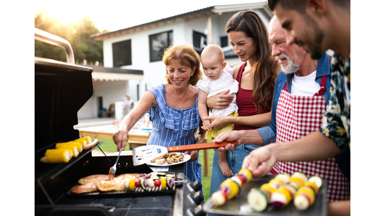 Portrait of multigeneration family outdoors on garden barbecue, grilling.