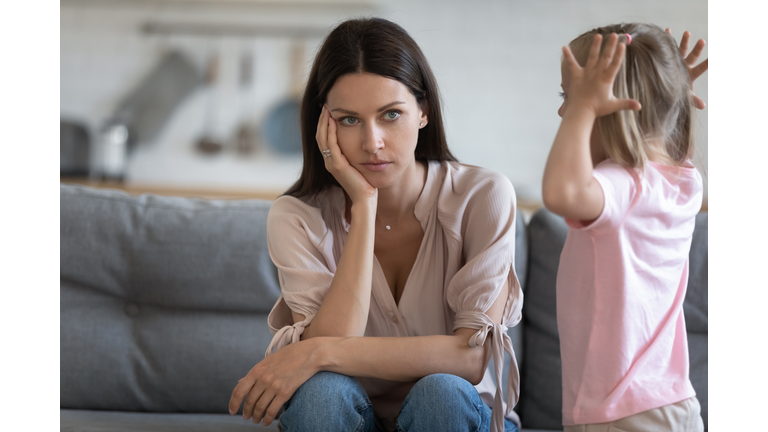 Unhappy mother having problem with noisy naughty little daughter