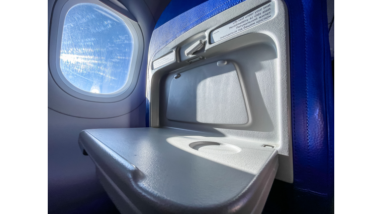 Low Cost Economy Airline Tray Table and Window in flight on a sunny day with copy space.