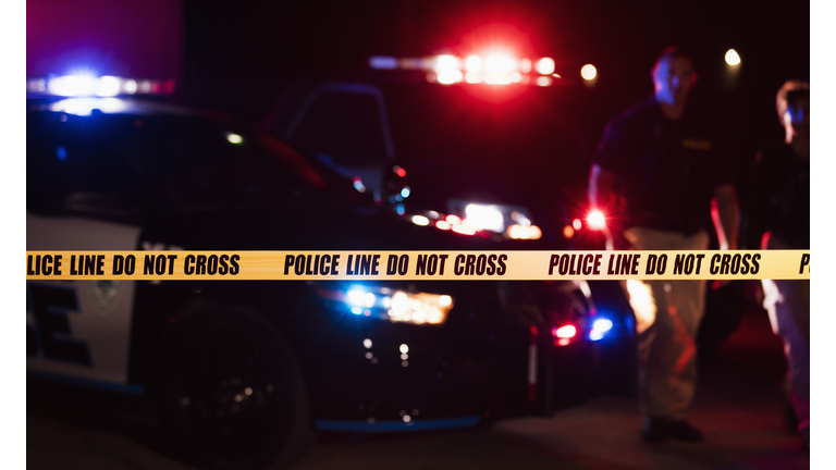 Two police officers behind crime scene tape