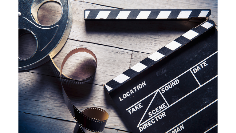 Film reel and movie clapper on wooden background