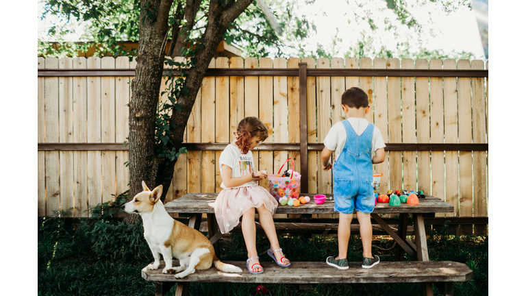Young brother and sister looking through easter eggs outside