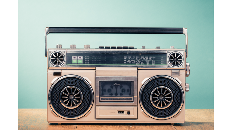 Retro outdated cassette tape recorder from 80s on table front mint green background. Vintage old style filtered photo