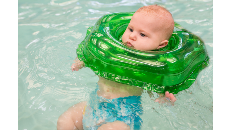 Baby swimming with help of inflatable ring.