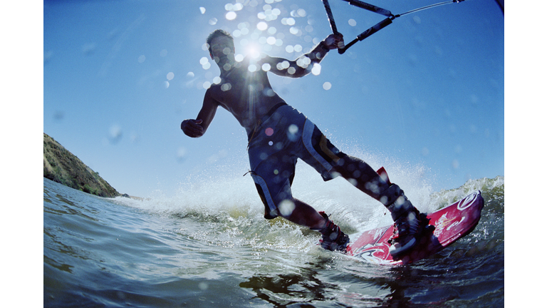Young man wakeboarding on lake, low angle view