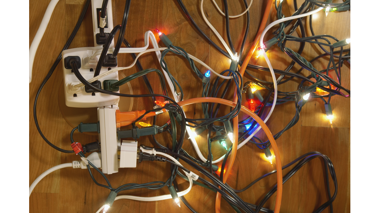 Tangled Christmas lights and electrical cords on hardwood floor