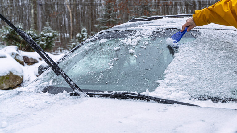 Man cleaning a car from the snow after a snowfall