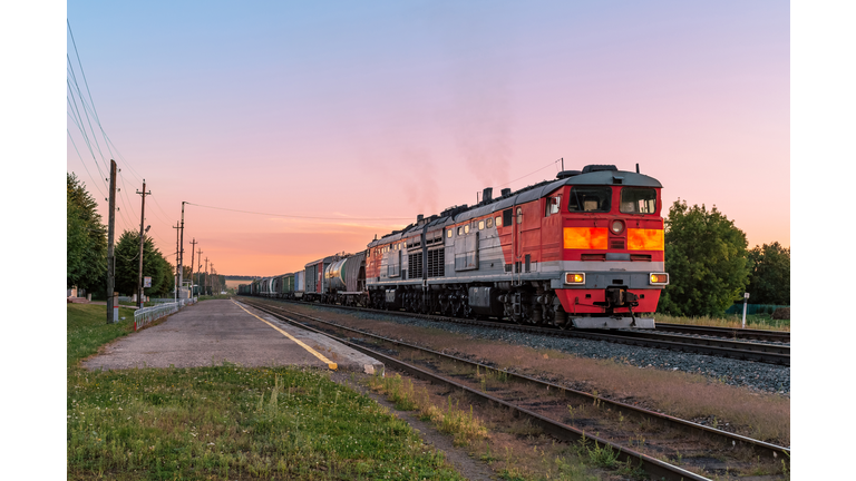 Powerful diesel locomotive with a heavy freight train in a beautiful sunset light