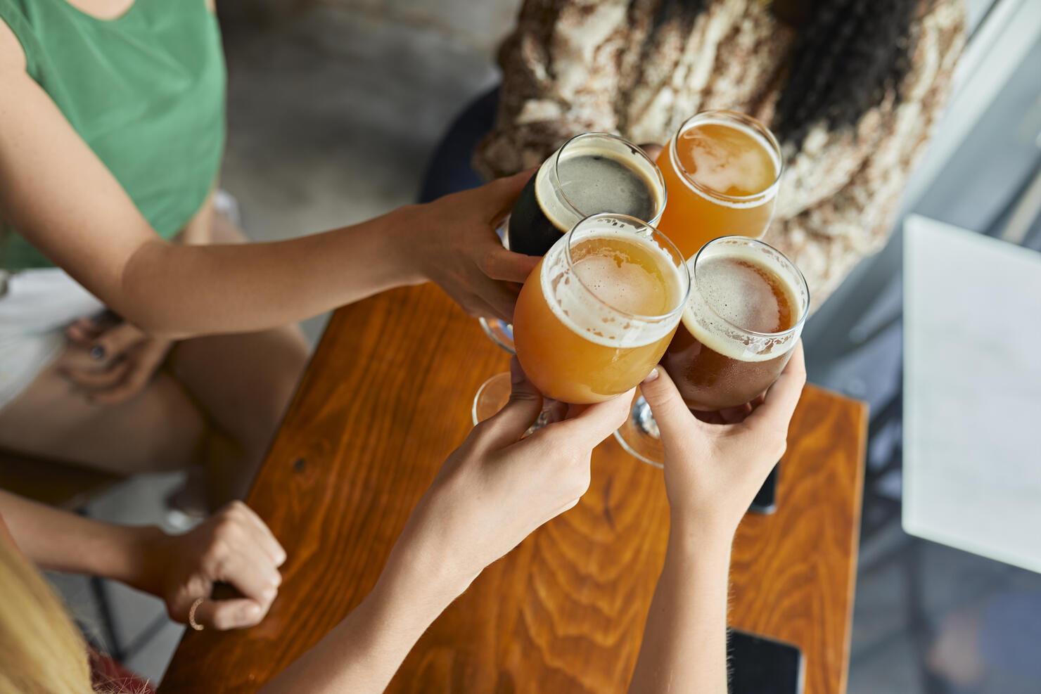 Female friends clinking craft beer glasses in a pub