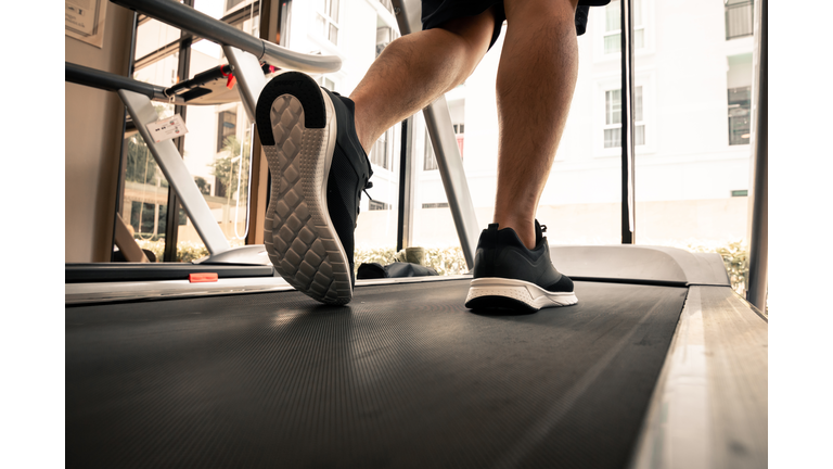 Man legs with sport shoes running on treadmill in fitness gym.