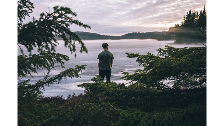 Hiker looking at the view over a lake in sunset.