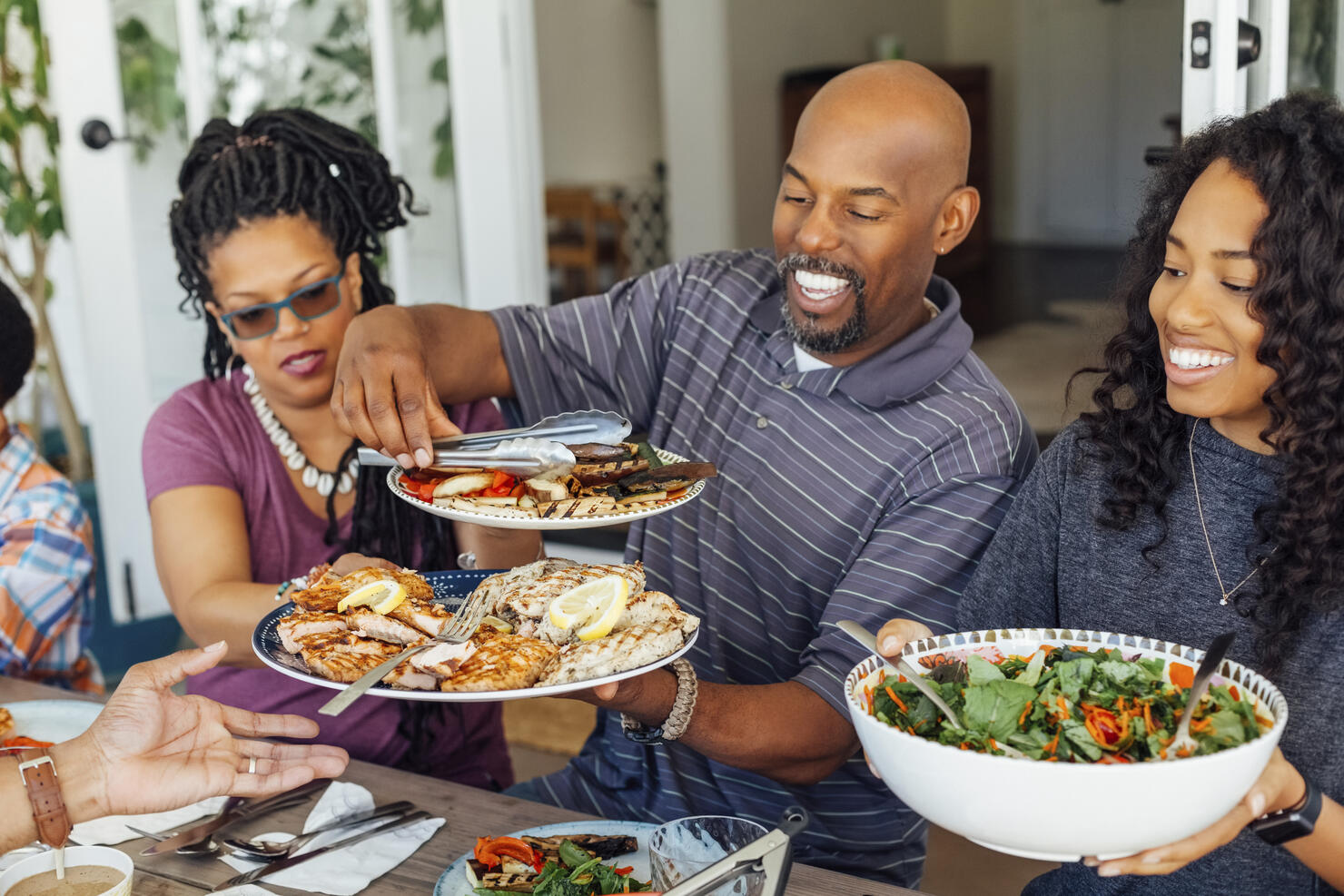 Smiling man serving food to family during outdoor dinner party