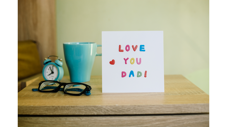 Greeting Card for Happy Father's Day, on the bed, paper white sheet with text Love You Dad and heart, colorful letters