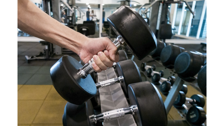 Human Hand holding dumbbell in gym