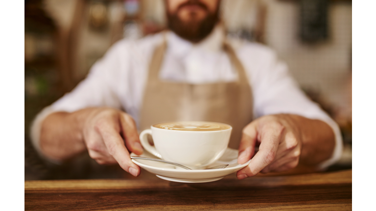 Barista serving cup of fresh coffee for you