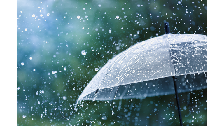 Transparent umbrella under rain against water drops splash background. Rainy weather concept.