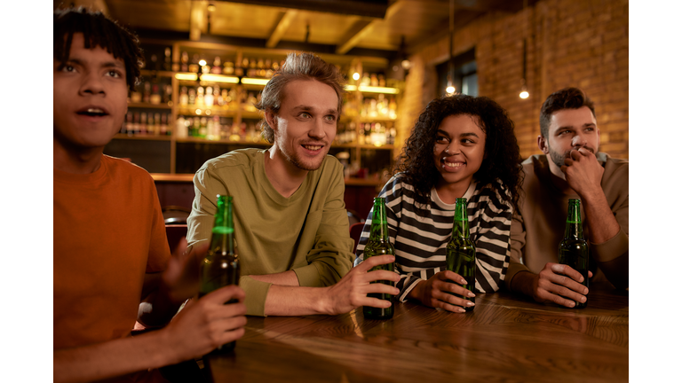 Keep calm and cheer on. Friends in the bar watching sports match on TV together, drinking beer and cheering for team. People, leisure, friendship and entertainment concept