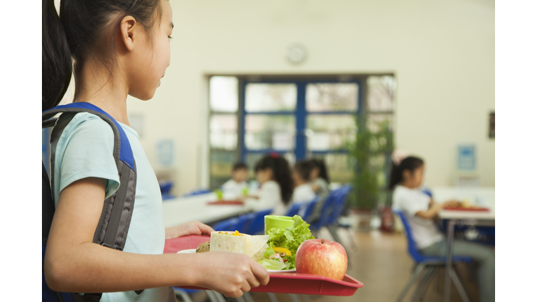 Girl holding food tray in school cafeteria