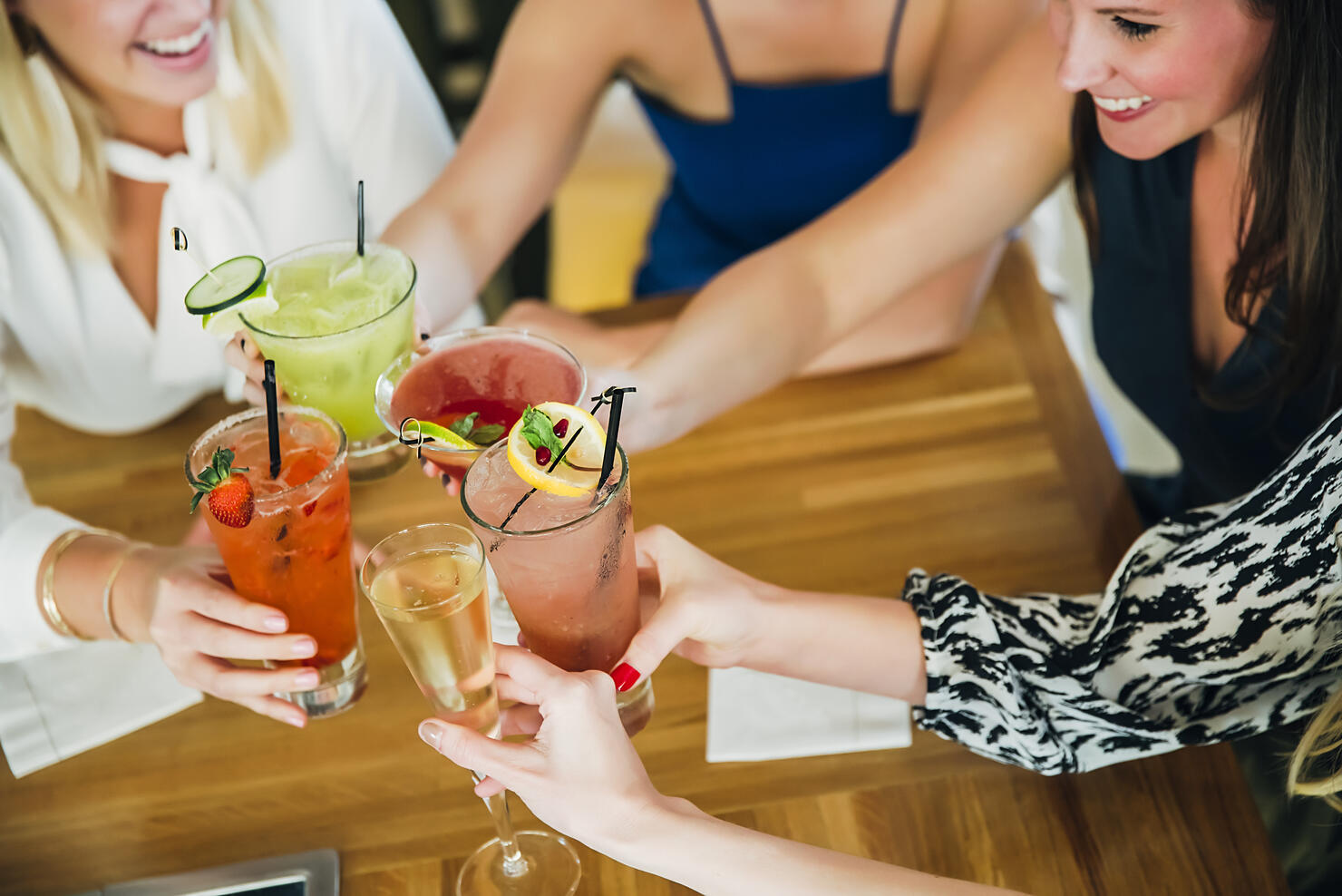 Caucasian women toasting at bar with cocktails