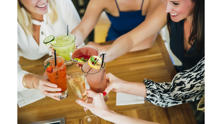 Caucasian women toasting at bar with cocktails