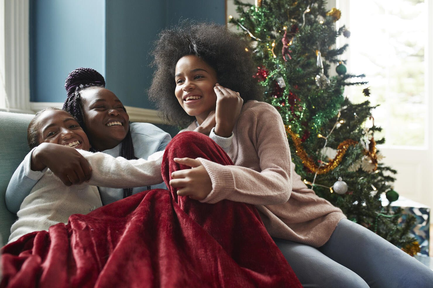 Happy sisters embracing while sitting on sofa