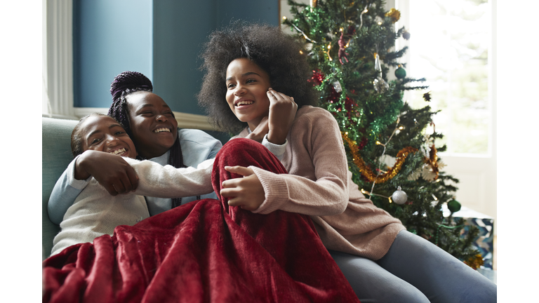 Happy sisters embracing while sitting on sofa