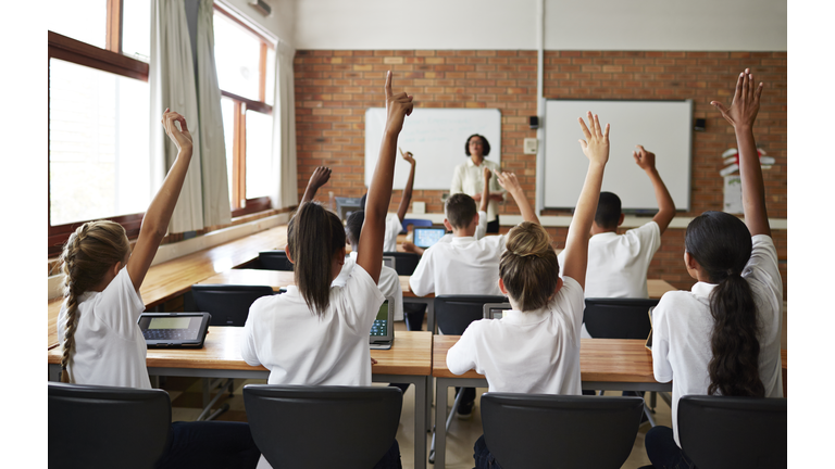 Back view of schoolclass with raised hands