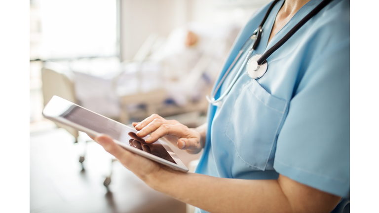 Midsection of nurse using tablet pc in hospital