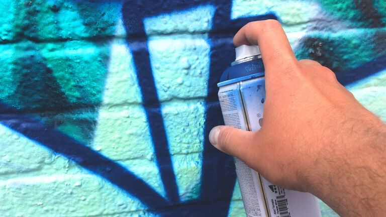 Cropped Image Of Hand Doing Spray Painting On Wall