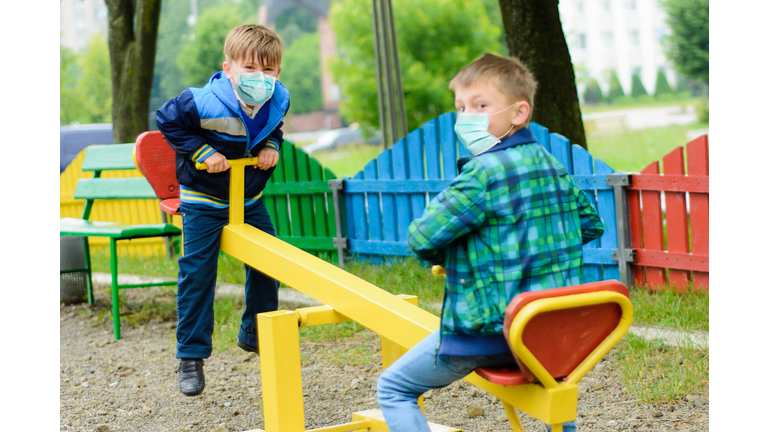 Children school in medical masks play at a quarantine playground during a coronavirus pandemic