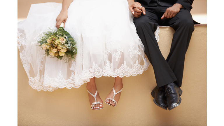 South Africa, Cape Town, Bride and groom sitting on wall