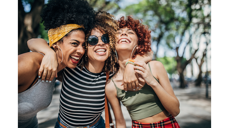 Three beautiful ladies hugging in city