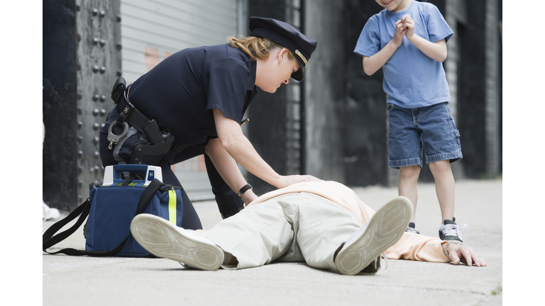 Woman police officer administering first aid to a senior man