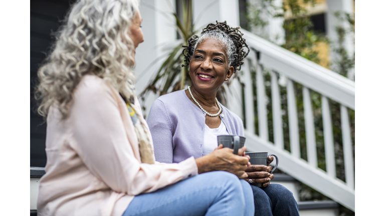 Senior women having coffee in front of suburban home