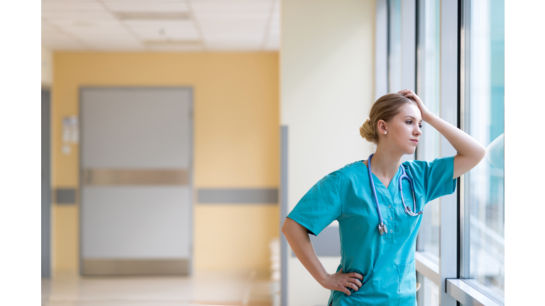 Tired female nurse in hospital corridor