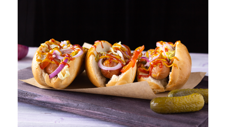 Hot dogs with vegetables, mustard and ketchup on a cutting board, side view Fast food, street food.