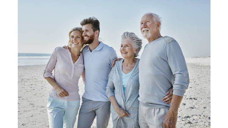 Smiling senior couple with adult children on the beach