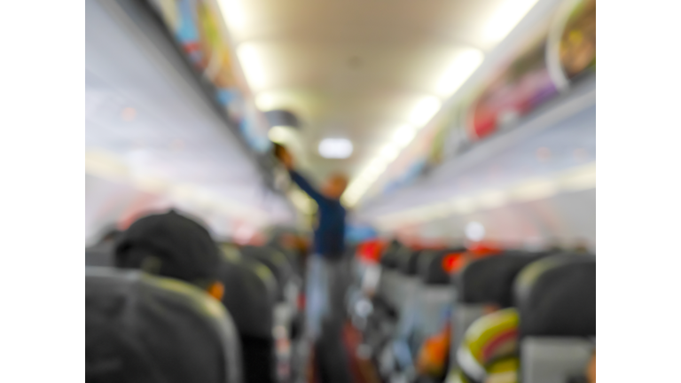 Blurred passenger put luggage in overhead locker