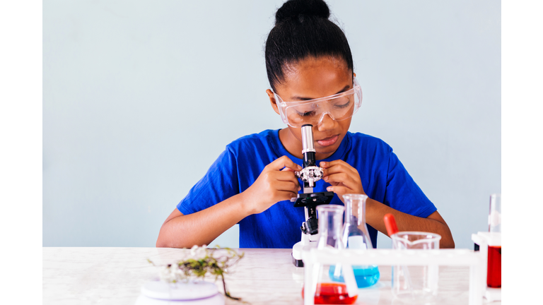 Young African American kid using microscope in lab