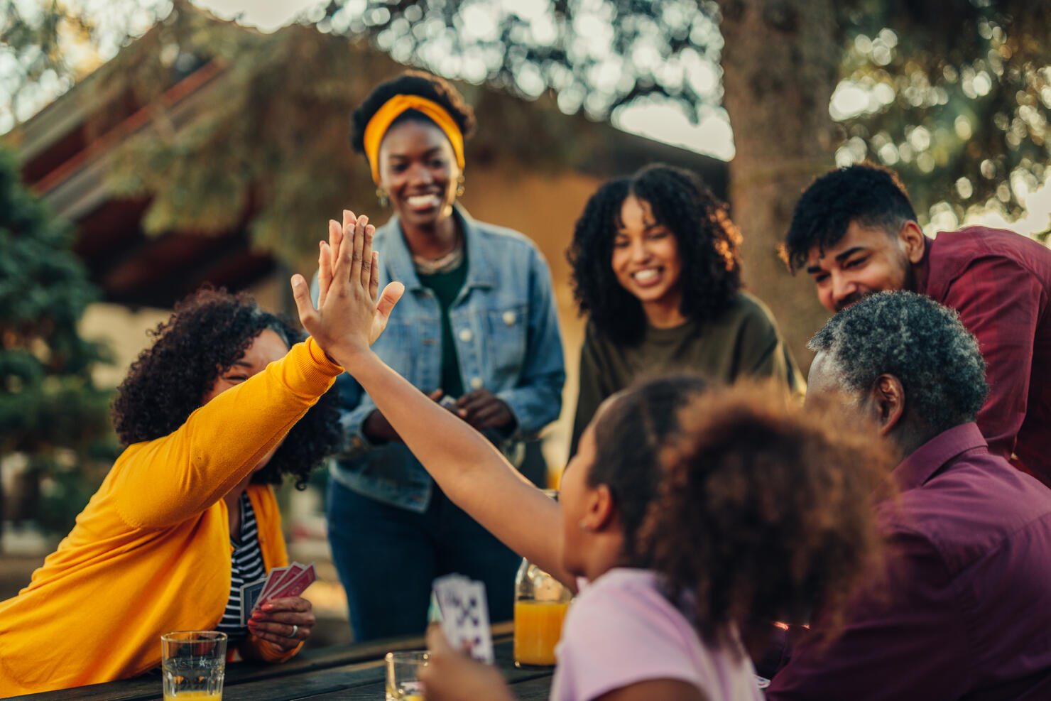 Girl and grandmother high five during playing cards with family members