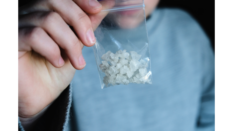 hand holds packet with white narcotic - cocaine, meth or another drug