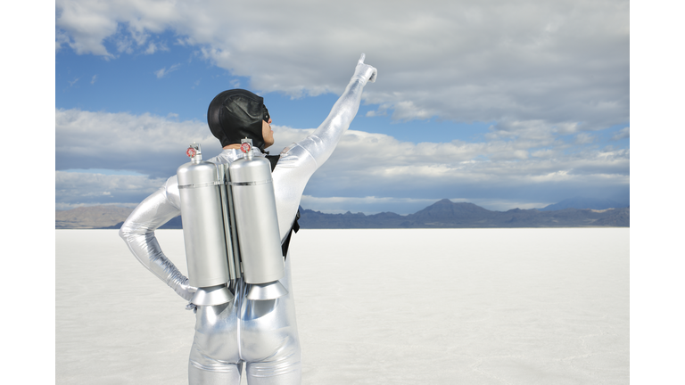 Man Wearing Jet Pack Pointing to Sky.