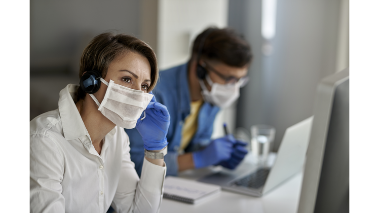 Pensive call center agent communicating with customer while working during coronavirus epidemic.