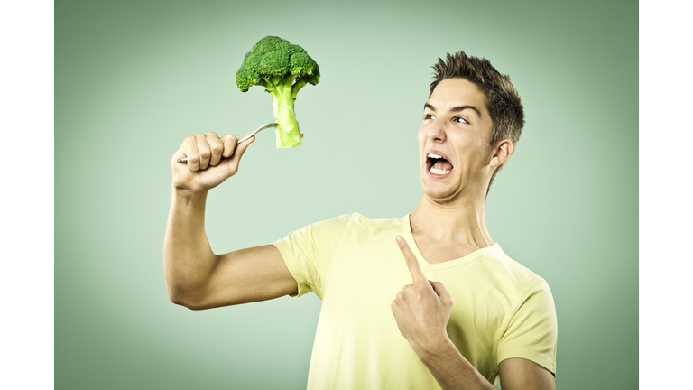 Unhappy boy with a broccoli